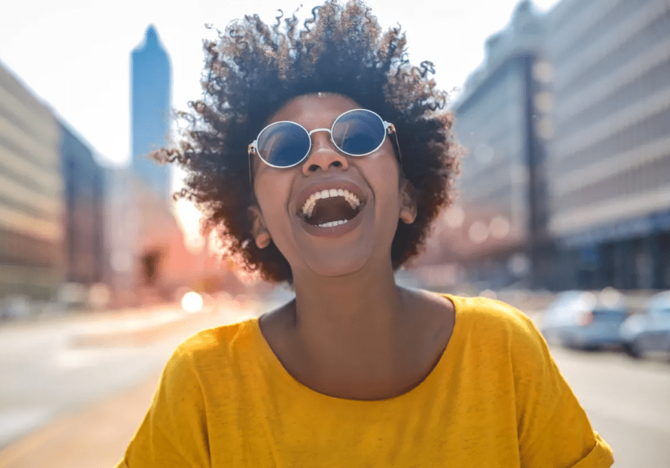 A woman with sunglasses on and smiling.