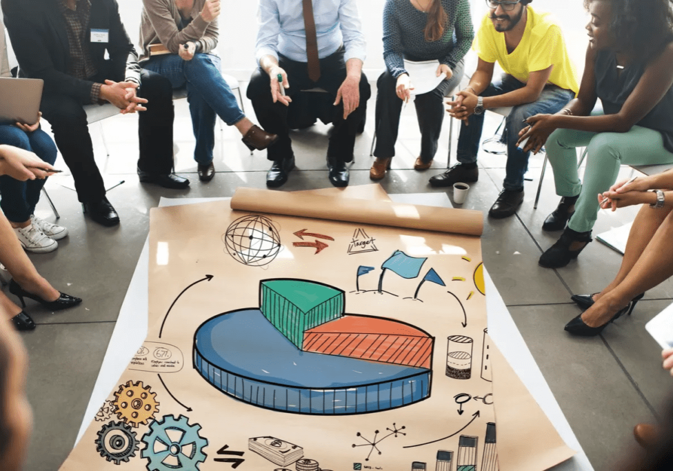 A group of people sitting around a large poster.